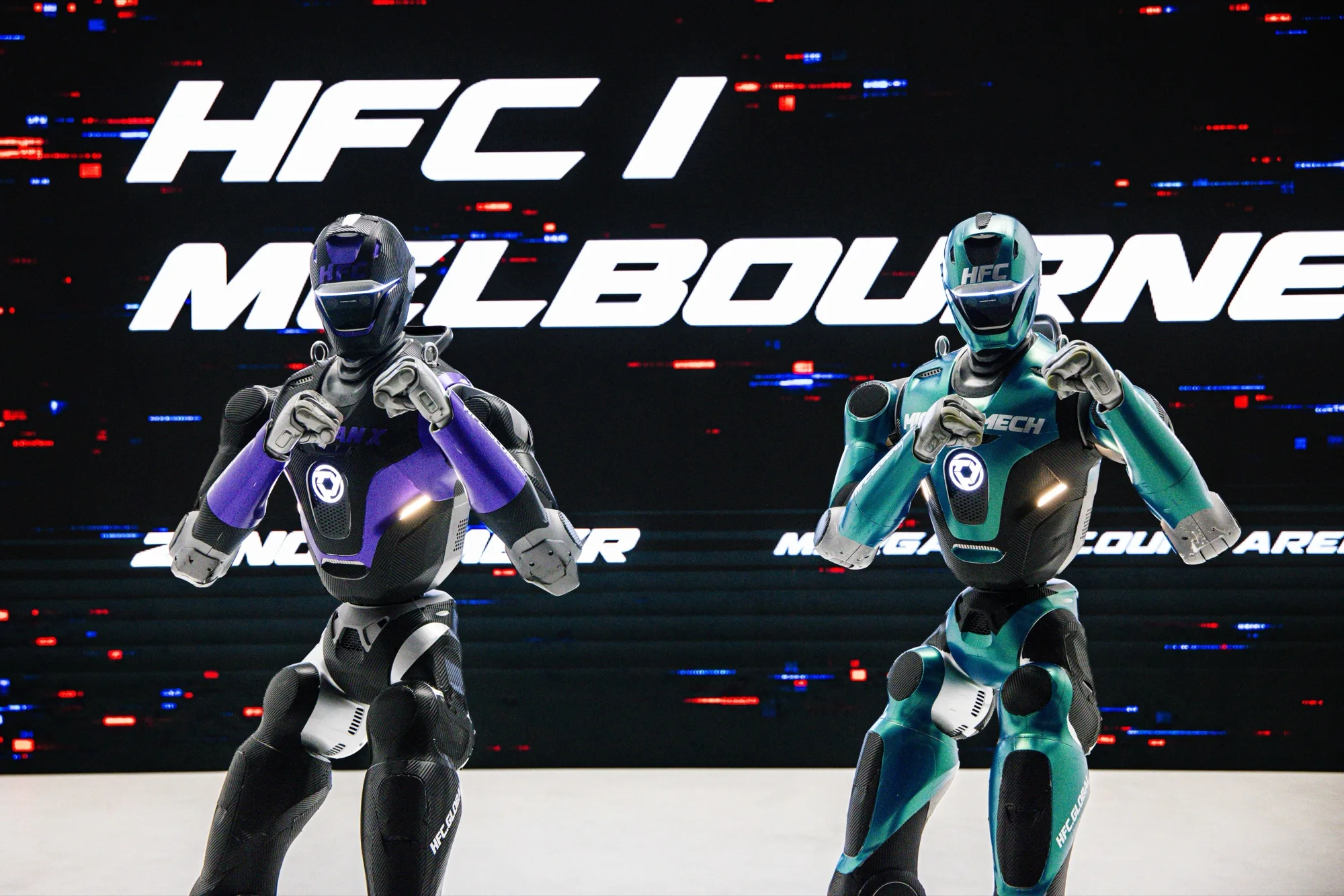 ADESAN-X and MIGHTY MECH in a fighting stance in front of a screen reading HFC I Melbourne, 21 November, Margaret Court Arena
